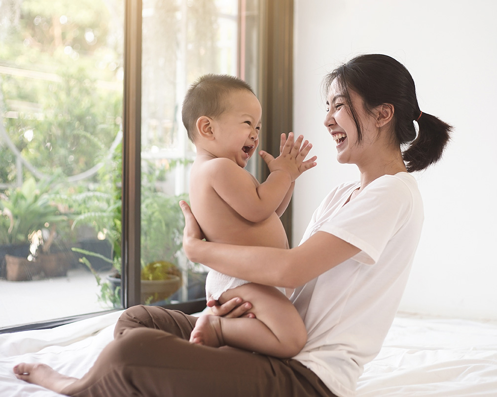 Asian mother playing with her baby in front of a door